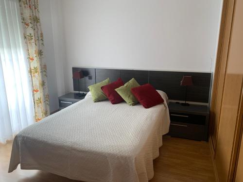 a bedroom with a bed with red and green pillows at Chalet Villa Maria a 10 minutos de Puy du Fou in Burguillos de Toledo