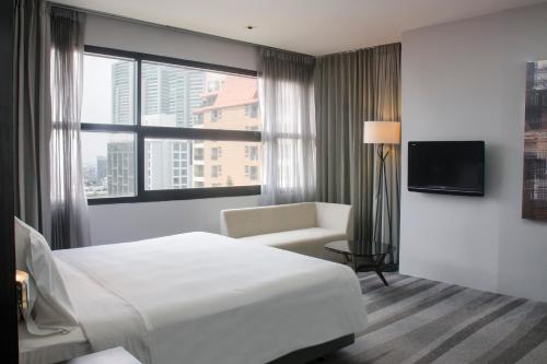 a hotel room with a bed and a chair and a window at Holiday Inn Bangkok Sukhumvit by IHG in Bangkok