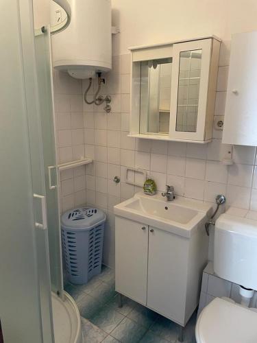 a white bathroom with a sink and a toilet at Apartment E&M in Pag