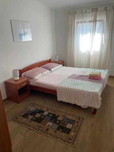 a bedroom with a bed and a window and a rug at Apartment E&M in Pag