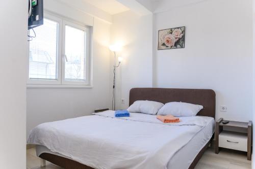 - une chambre dotée d'un grand lit avec des draps blancs et une fenêtre dans l'établissement Apartman Saga Premium Garaza Parking Vauceri Ne, à Sokobanja