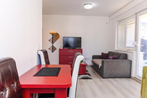 a living room with a red table and a couch at Apartman Saga Premium Garaza Parking Vauceri Ne in Soko Banja