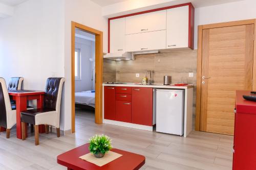 eine Küche mit roten Schränken und einem Tisch im Zimmer in der Unterkunft Apartman Saga Premium Garaza Parking Vauceri Ne in Sokobanja