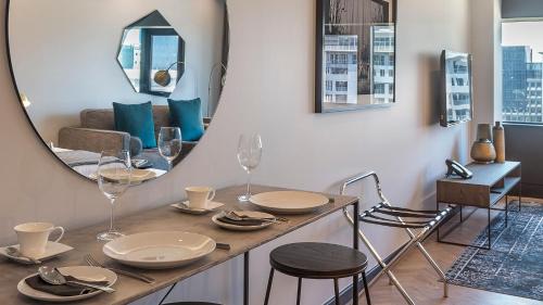 a dining room with a table and a mirror at The Onyx Apartment Hotel by NEWMARK in Cape Town