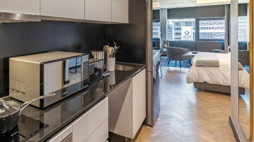 a kitchen with a microwave and a bed in a room at The Onyx Apartment Hotel by NEWMARK in Cape Town