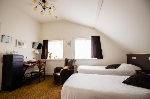 a bedroom with two beds and a desk with a chair at Hotel de Reiziger in Ottersum