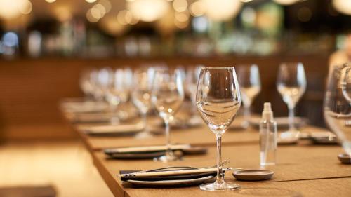 a row of wine glasses on a wooden table at The Onyx Apartment Hotel by NEWMARK in Cape Town