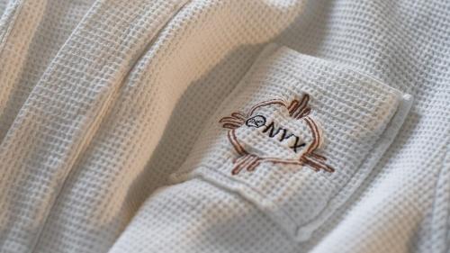 a small embroidered bird on a white dress at The Onyx Apartment Hotel by NEWMARK in Cape Town