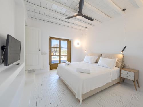 a white bedroom with a bed and a flat screen tv at AG VILLAS in Mýkonos City