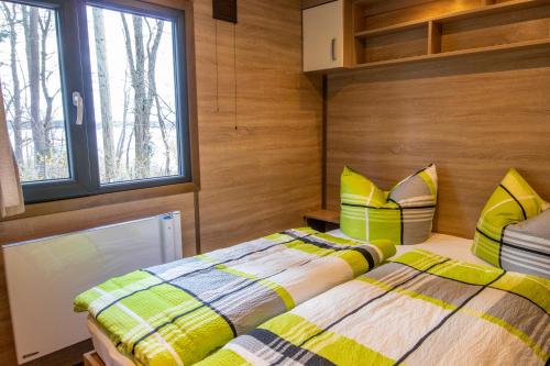 two beds in a room with wooden walls and windows at Mobilheime am See in Lychen