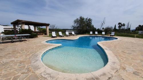 una grande piscina con sedie e gazebo di CAN FARITZEO a Sant Rafel de sa Creu