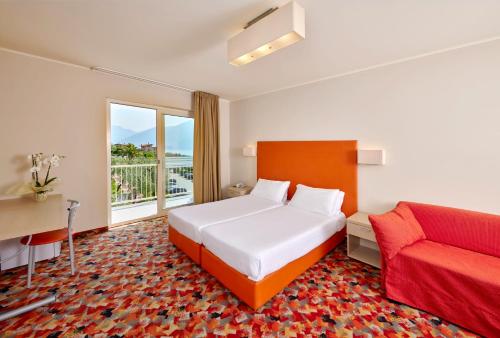 a bedroom with a bed and a desk and a couch at Hotel Royal Village in Limone sul Garda