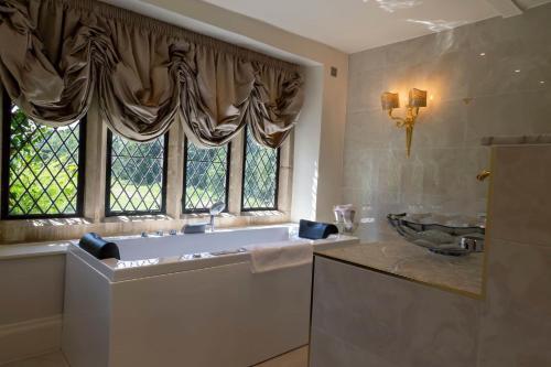 baño con bañera, lavabo y ventana en Weston Manor Hotel, en Bicester