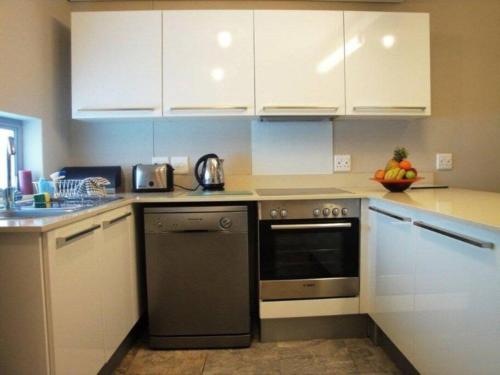 a kitchen with white cabinets and a black dishwasher at 312 HARBOUR BRIDGE in Cape Town