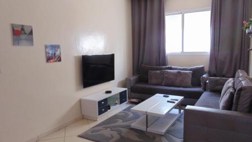 a living room with a couch and a tv at Suite Apartment Fawzi in Agadir