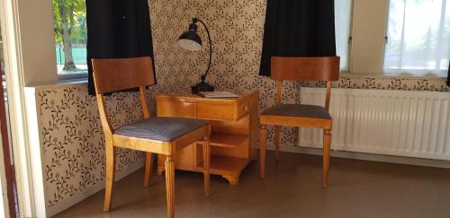 two chairs and a desk in a room with a window at Villa Eira vandrarhem in Hjo