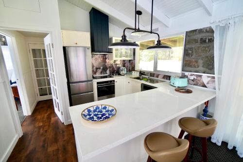 a kitchen with a white counter with stools in it at Elegant bluestone cottage located at the Red Hill Peony Estate in Red Hill