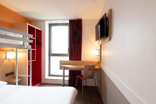 a small room with a desk and a bed and a window at Premiere Classe Le Havre Centre-LES DOCKS in Le Havre