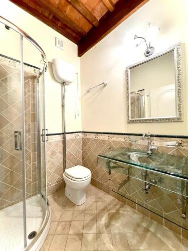 a bathroom with a sink and a toilet and a mirror at Villa Conti in Fauglia
