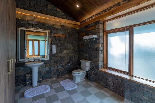 a bathroom with a toilet and a sink and a window at StayVista at Mountain Mirage in Solan