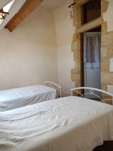 deux lits dans une chambre avec des draps blancs dans l'établissement Maison de caractère au cœur de la cité médiévale de Gourdon, à Gourdon