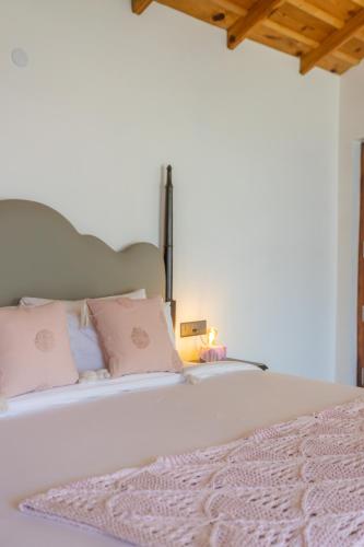 a bedroom with a white bed with pink pillows at Seclude Ramgarh Willows in Rāmgarh