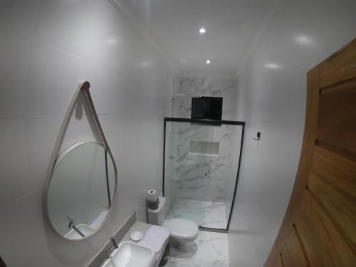 a white bathroom with a toilet and a mirror at Sunshine - Casa de praia em Barra Grande -Ba in Barra Grande