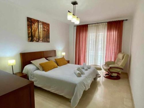 um quarto com uma cama grande e uma cadeira em Chicflat Avenida España Ideal para familias em Estepona