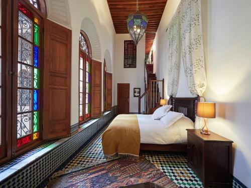 Schlafzimmer mit einem Bett und Buntglasfenstern in der Unterkunft Dar Roumana in Fès