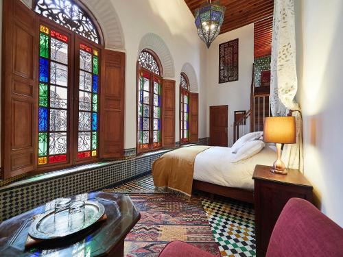 una camera con letto e vetrate istoriate di Dar Roumana a Fes