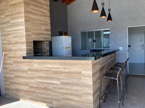 a kitchen with a counter with stools and a refrigerator at Recanto Asa Delta in Olímpia