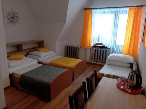 a bedroom with three beds and a table and a window at Willa Halusia in Zakopane