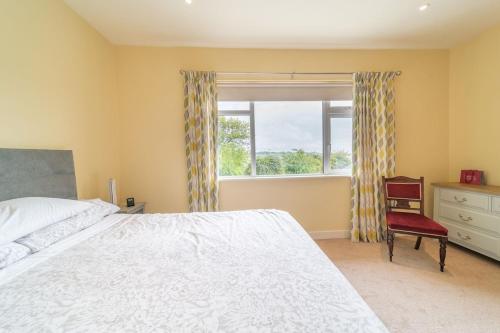 1 dormitorio con cama, ventana y silla en 2 BED WATERFRONT PROPERTY - CLOSE TO COURTMACSHERRY en Cork