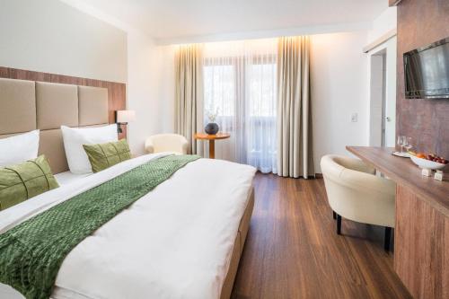 a hotel room with a large bed and a desk at Hotel Lorenz in Bad Füssing