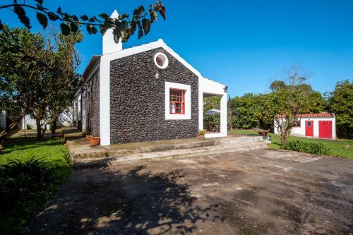 a stone church with a red door at Quinta dos Reis in Biscoitos