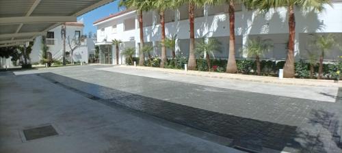 an empty street in front of a building with palm trees at Hostal Las Cumbres in Conil de la Frontera