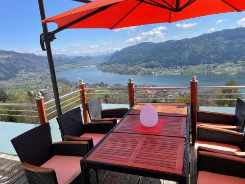 a table with an umbrella on a deck with a view at Mathiasl Wellness-Ferienhäuser in Bodensdorf