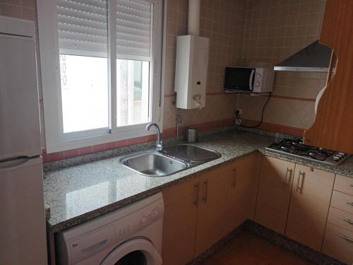 una pequeña cocina con fregadero y ventana en atico centrico nervion, en Sevilla
