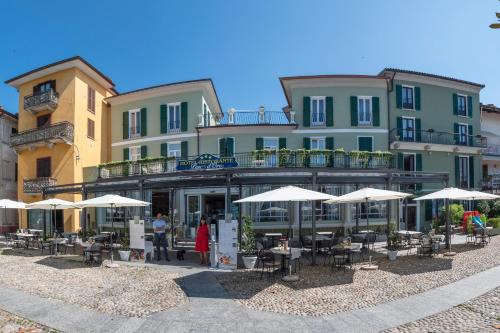 a building with tables and umbrellas in front of it at Albergo Pesce D'oro in Verbania