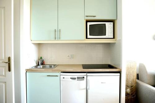 uma cozinha com armários brancos, um lavatório e um micro-ondas em Chez Adriana Studio Proche Mer avec Piscine em Grimaud
