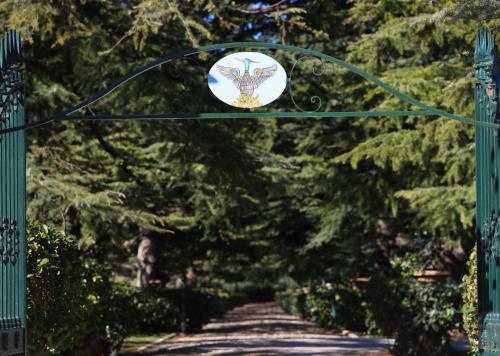 un cancello verde con un cartello sugli alberi di Villa Fenicia a Ruvo di Puglia