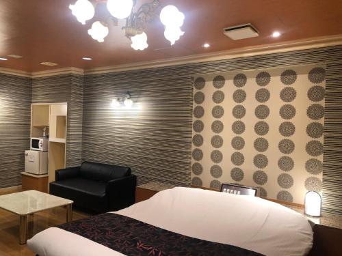 um quarto com uma cama e uma cadeira preta em ホテルハンズ em Ginan