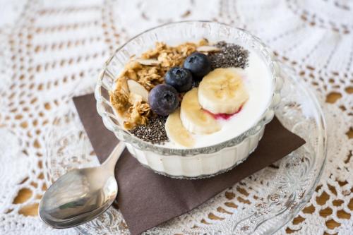 a bowl of granola and fruit on a plate with a spoon at Hiša Poljana Rooms in Prevalje