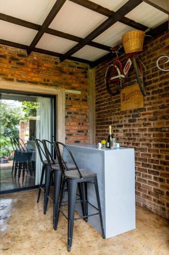 a kitchen with a bar with chairs and a brick wall at Belvidere Country Estate in Karkloof Nature Reserve