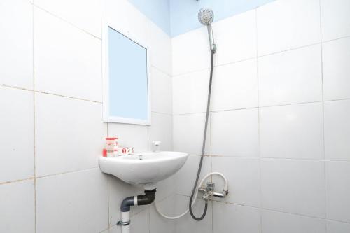 Baño blanco con lavabo y espejo en Super OYO 1414 Paviliun Permata, en Solo