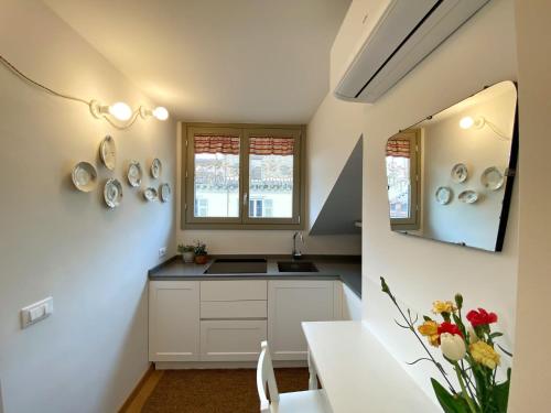 kuchnia z białymi szafkami, umywalką i lustrem w obiekcie Casa Ginepro via Mazzini w Turynie