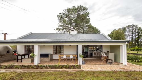 a white house with a patio and dining area at Belvidere Country Estate in Karkloof Nature Reserve