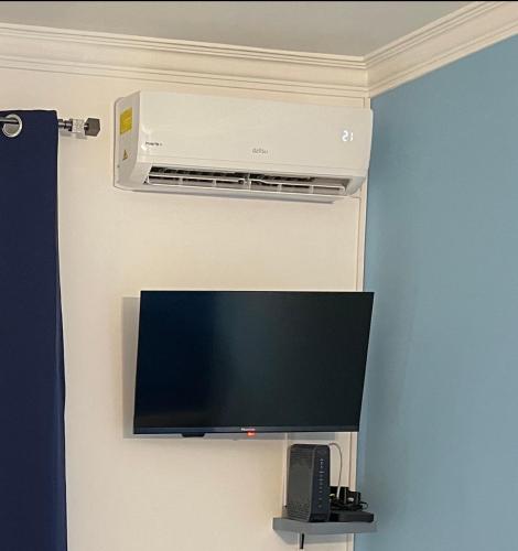 a flat screen tv on a wall with a air conditioner at Miguel Torga River in Coimbra