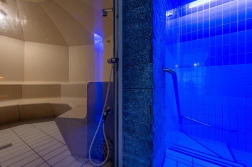 ein Bad mit einem WC und einer Dusche mit blauen Lichtern in der Unterkunft Arenas Resort Victoria-Lauberhorn in Wengen