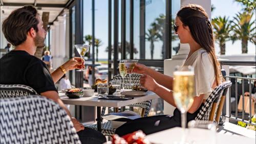 a man and woman sitting at a table drinking wine at The Winchester Hotel by NEWMARK in Cape Town